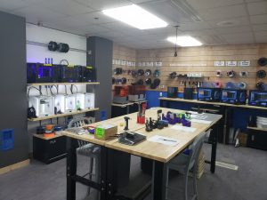 An array of operational 3D printers and neatly organized filament spools on shelves in the well-equipped Catalyst Space.
