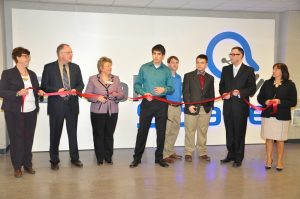 Ribbon-cutting ceremony at Catalyst Space with seven individuals, including the founder, community members, and local dignitaries, standing in front of a Catalyst Space logo. They are indoors, holding a red ribbon, ready to celebrate the opening.